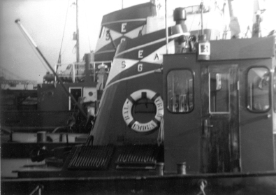 Schleppschiffe helfen  dem Schiff RHEINSTEIN BREMEN im Jahr 1967 beim Auslaufen aus dem Emder Hafen.