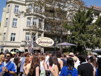 Farbfoto von feiernden Menschen neben dem Umzug vom Karneval der Kulturen auf der Straße Hasenheide in Berlin am 28. Mai 2023. Fotograf: Erwin Thomasius.