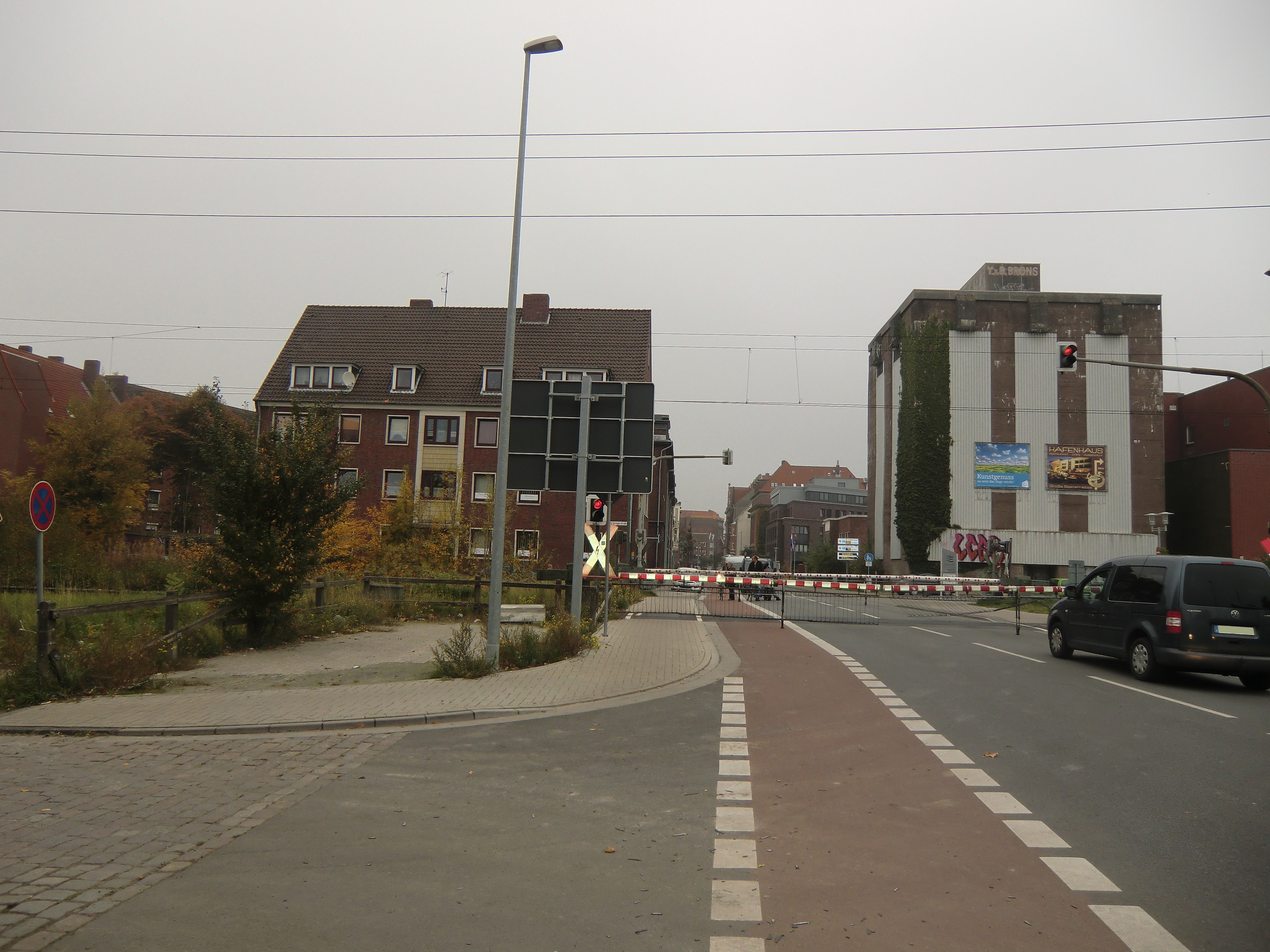 Farbfoto: Eine geschlossene Schranke an der Eisenbahnstrecke Leer-Emden versperrt die Nesserlander Straße. Links vor der geschlossenen Schranke biegt die Küstenbahnstraße von der Nesserlander Straße nach links ab. In Emden im Oktober des Jahres 2012. Foto: Erwin Thomasius.